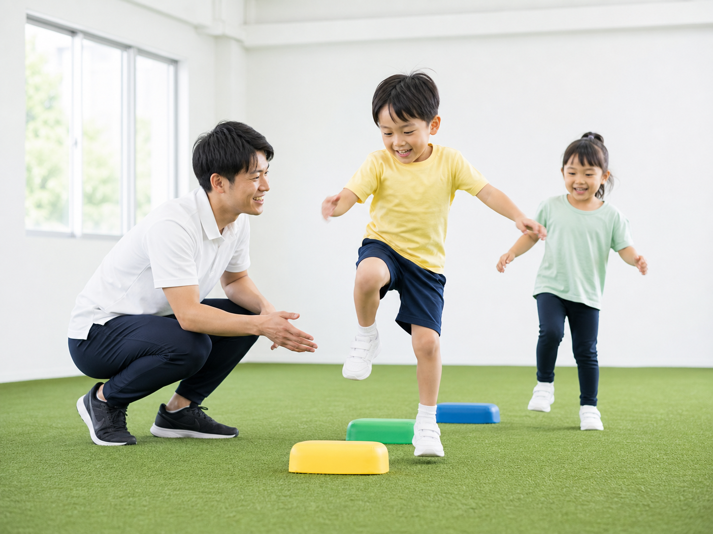 白く明るい室内の人工芝でコーチと運動する子ども